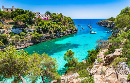 Yachts anchored in turquoise waters in a secluded anchorage in the Balearics