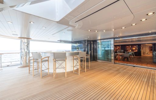Aft deck onboard charter yacht CARINTHIA VII, wet bar in the foreground with gray stool seats and open entrance to the interiors