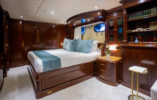 Master cabin onboard charter yacht PURPOSE, central berth facing forward with bookshelf and bureau in the foreground
