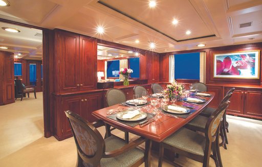 the sleek and luxurious banquet styled dining table inside the main salon of charter yacht lady J