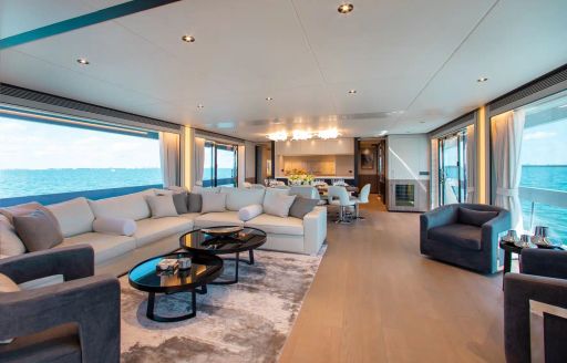 Main salon onboard charter yacht FREEDOM, spacious lounge area in the foreground with large windows on either side