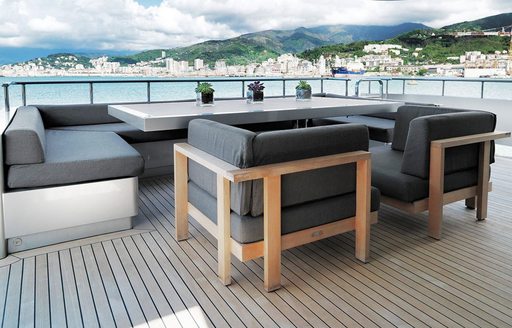 Alfresco dining set up onboard charter yacht NAIA, slim line dining table surrounded by gray upholstered seating