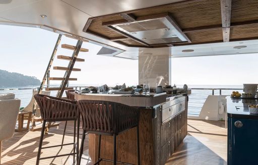 A wet bar on the aft deck onboard charter yacht KING BENJI, with wicker stools and surrounding views of the sea