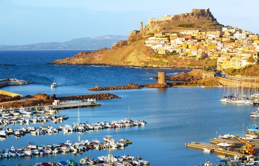 yacht harbour with citadel on a hilltop in the background in sardinia