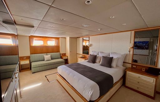 Master cabin onboard charter yacht GENESIA, central berth facing forward with seating area in the background