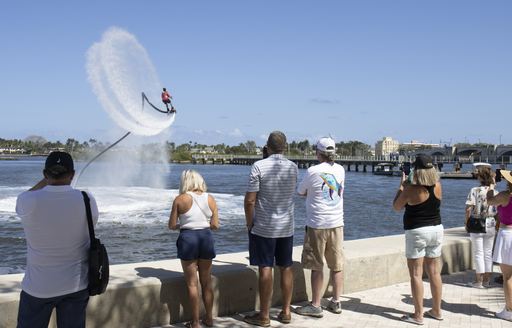 A flyboarding demonstrator in action with visitors watching from the dockside at the Palm Beach International Boat Show