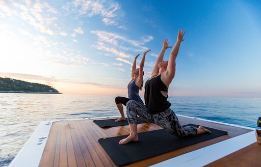 Two models perform yoga on the swim platform of a superyacht