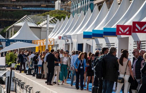 people and showgoers looking at the stands at the Monaco Yacht Show