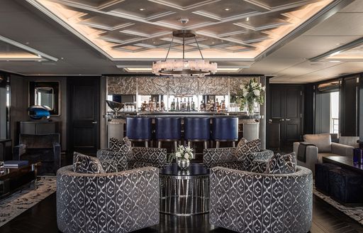 bar area in main salon of superyacht aquila with grey decor and crystal chandeliers
