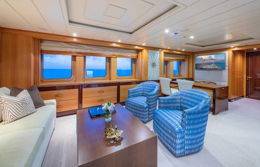 Private lounge area in the master cabin onboard charter yacht NITA K II, white sofa and two blue armchairs facing each other over low coffee table