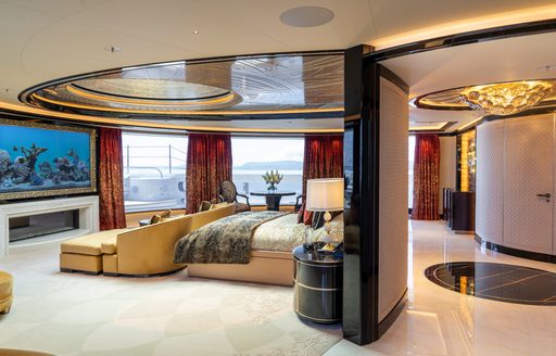 Master cabin onboard superyacht charter KISMET, central berth facing wall mounted TV, surrounded by full-height windows