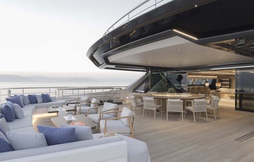 Overview of the aft deck onboard charter yacht MALIA. Ample plush seating in the foreground with alfresco dining behind
