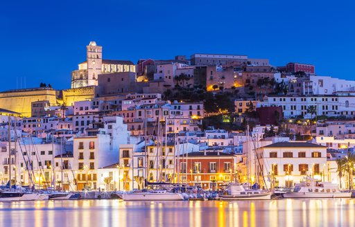 Mesmerizing Ibiza town at night with gorgeous lights reflecting on the water's surface.