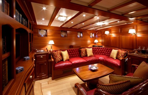 red leather sofa, armchairs and bookcase in the main salon aboard sailing yacht ELENA