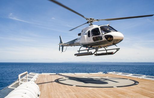 A helicopter coming in to land on the helipad of charter yacht SURI