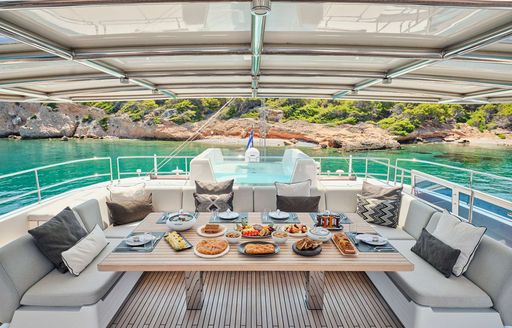 Aft deck onboard charter yacht ABOVE & BEYOND, alfresco dining option with views of a bay