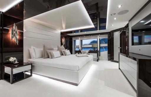 large bed with white upholstery in the master suite aboard luxury yacht Berco Voyager