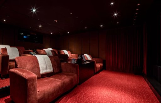 Indoor cinema with plush red seats onboard superyacht charter OCTOPUS