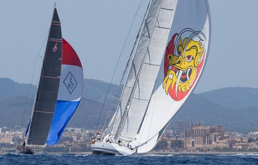 sailing yachts compete at the Superyacht Cup Palma 2018 with Palma Cathedral in background