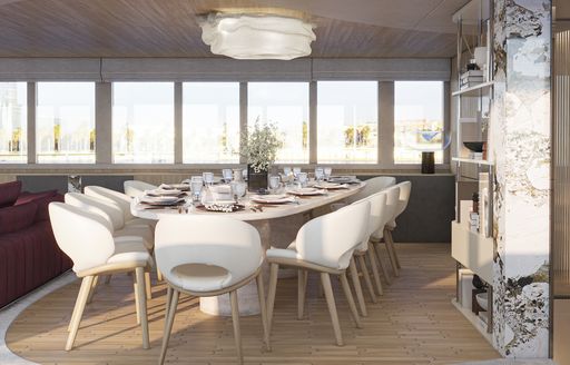 Overview of the interior dining area onboard charter yacht REPOSADO, long table with white dining chairs and extensive windows in the background