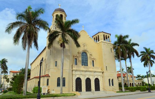 Frontal view of St. Edward Roman Catholic Church, Palm Beach, Florida. Surrounded by palm trees.