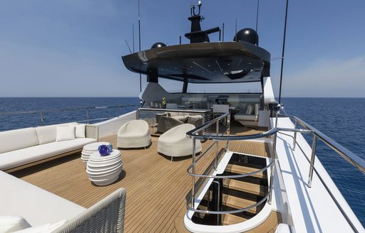Overview of the sun deck onboard charter yacht Never Give Up, white seating to port and surrounding views of the sea