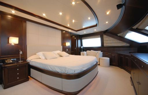 elegantly styled master suite with dark wood and light coloured upholstery aboard charter yacht ‘Elena Nueve’ 