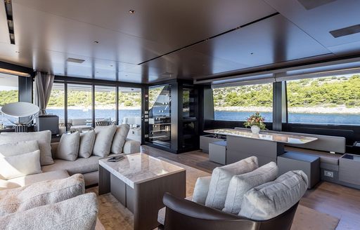 Main salon lounge area onboard charter yacht JICJ, with plush white and gray seating and surrounding windows