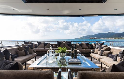 Exterior lounge area onboard charter yacht TRIUMPH, with multiple gray sofas facing a large coffee table