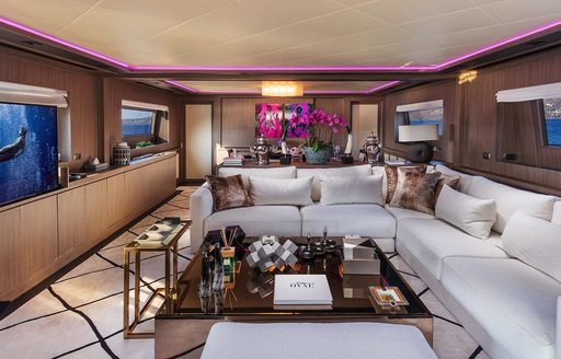 Main salon onboard charter yacht OVAL, with lounge area in the foreground and dining aft