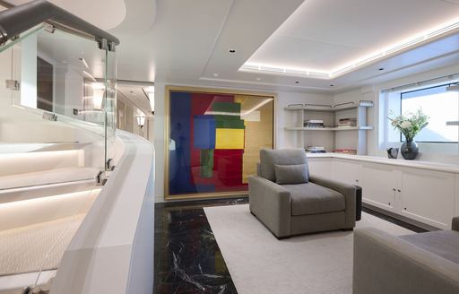 Small interior seating area onboard charter yacht ARBEMA, gray armchair with colorful artwork aft