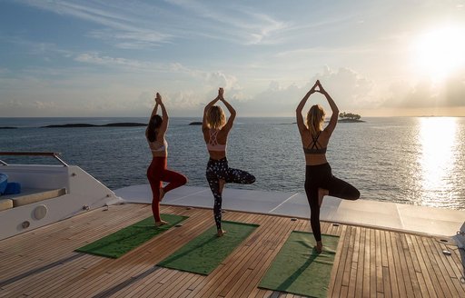 guests on a luxury yacht charter enjoying their vacation by doing some morning yoga to welcome in the sun 