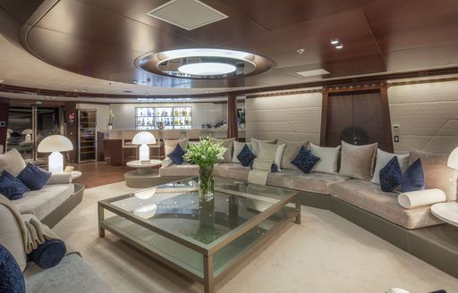 Main salon on luxury yacht KATINA with skylight letting light in and glass table with flowers on it