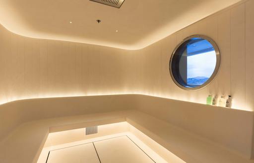 sauna/ steam room on luxury yacht faith, with bench seating and porthole