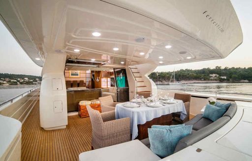 Overview of the aft main deck onboard charter yacht ORLANDO L, with alfresco dining set up center