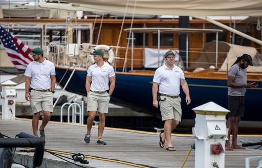A group of superyacht charter crew walking along a pontoon at the Newport Charter Yacht Show