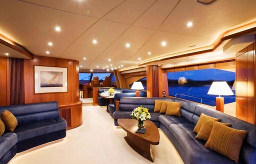 navy blue sofas and rich woods in main salon of charter yacht ALANI 