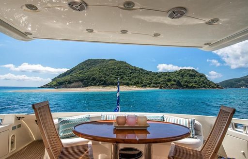 Alfresco dining on the aft main deck onboard charter yacht MANU with an island in the background