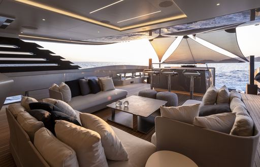 Overview of the aft main salon onboard NO STRESS TWO, extensive seating arrangement overlooking a canopy on the aft main deck.