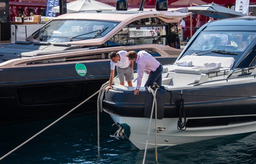 Two men looking over the front of a bow on a motor yacht berthed at the Monaco Yacht Show