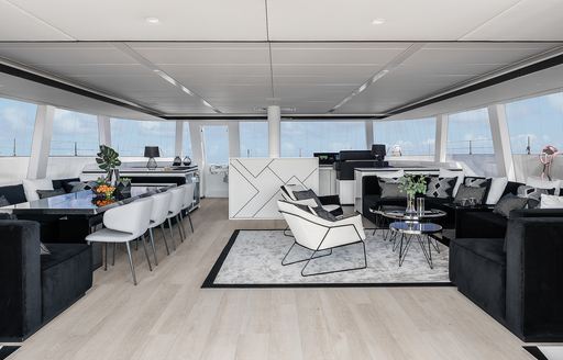Interiors onboard charter yacht ABOVE & BEYOND, monochrome aesthetics with dining area to port and lounge starboard