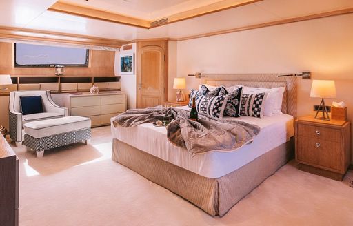 Master cabin onboard charter yacht NATALIA V, central berth facing forward with plush seating and a window in the background
