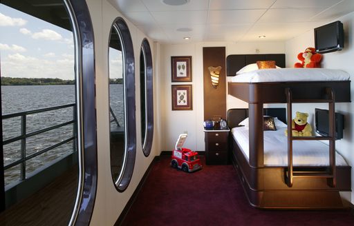 childrens cabin on luxury yacht global, with bunk beds covered in toys and windows overlooking the Caribbean sea