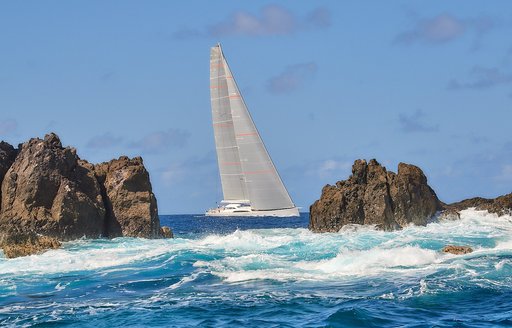 Sailing yacht framed between rocks on the horizon at St Barths Bucket Regatta