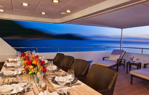 dining table on the upper deck aft of motor yacht Milk and Honey is setup for dinner