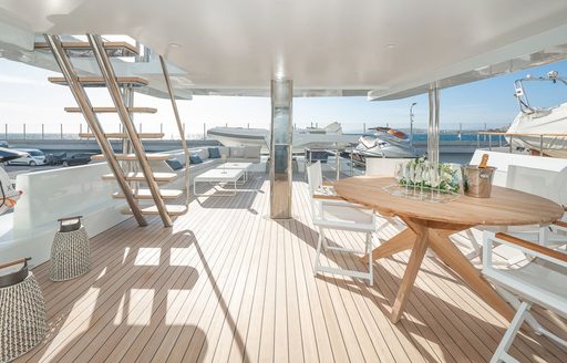 Overview of the aft main deck onboard charter yacht GELLY, with alfresco dining in the foreground and a lounge area in the background