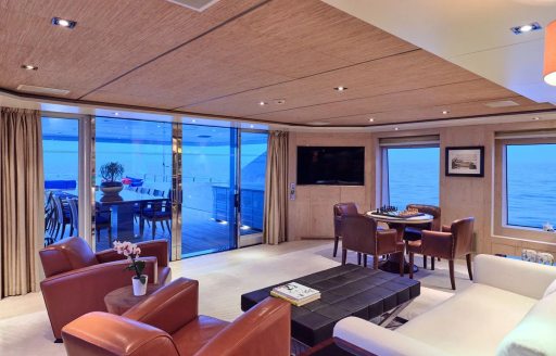 Upper salon onboard charter yacht TIMBUKTU, brown leather seating with views out of aft glass doors