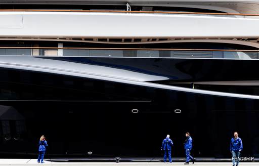 Construction team of Feadship Project 821 walking on the dock alongside the superyacht