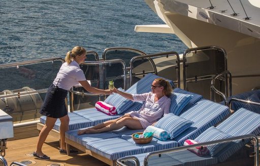 woman receives drink from sun lounger of superyacht JO