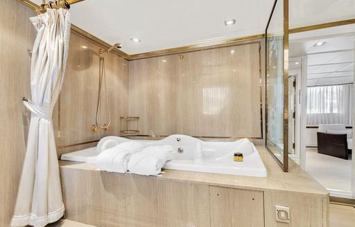 large tub on board luxury superyacht, with robes and towels alongside